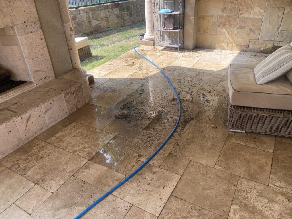 Wet patio tiles with blue hose present.